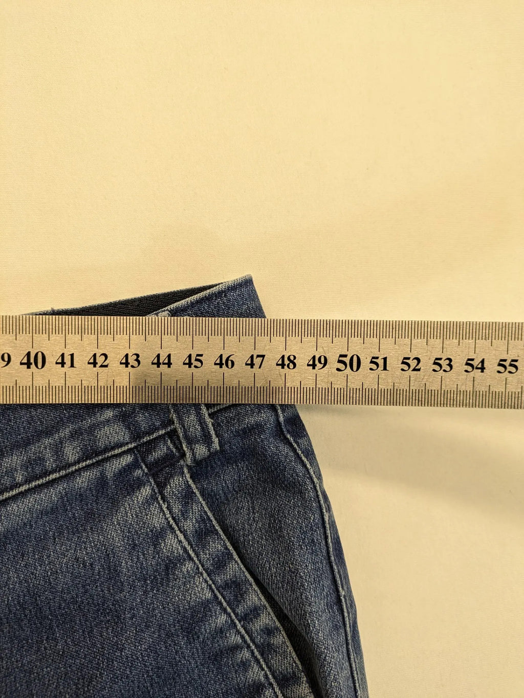 REI blue straight jeans with front pleats, zip fly, and buttoned back pockets.