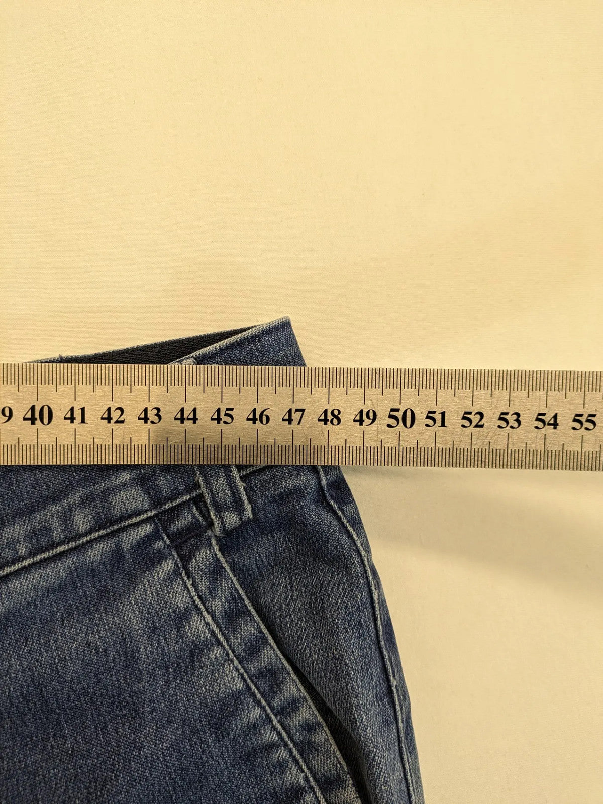 REI blue straight jeans with front pleats, zip fly, and buttoned back pockets.