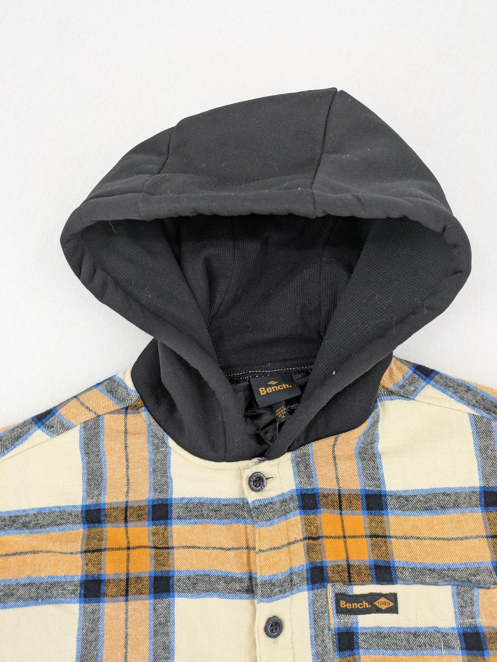 Bench cream flannel jacket with check pattern, black hood, and button placket.