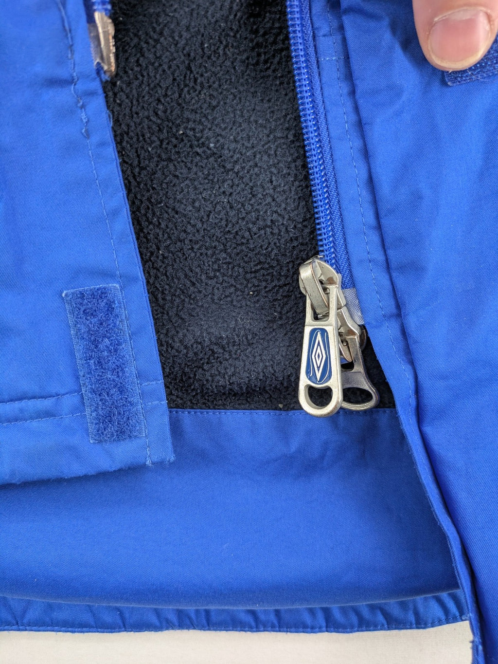 Umbro blue fleece-lined jacket with hood, reflective details, and white piping.