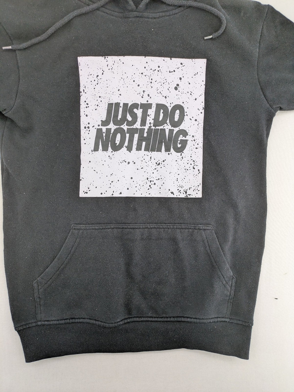 FSBN white zip-through hoodie with "Just Do Nothing" graphic and adjustable drawstring hood.