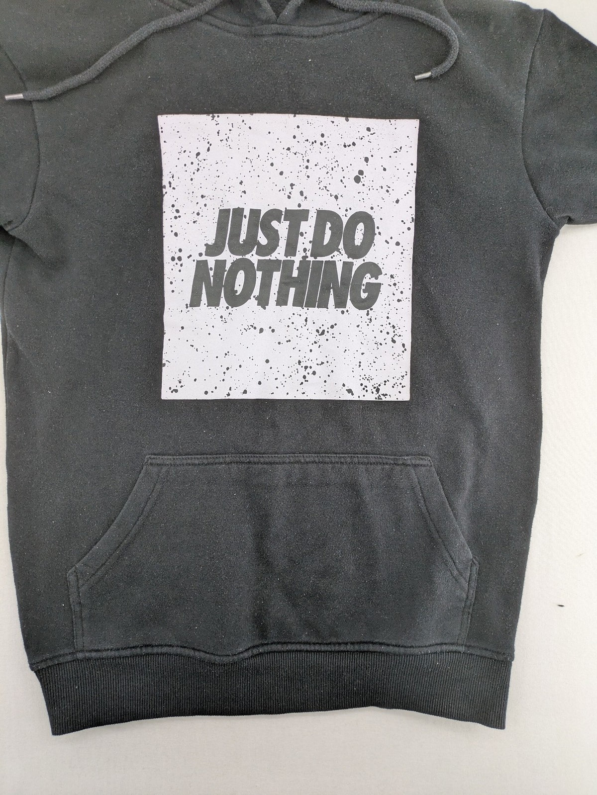 FSBN white zip-through hoodie with "Just Do Nothing" graphic and adjustable drawstring hood.