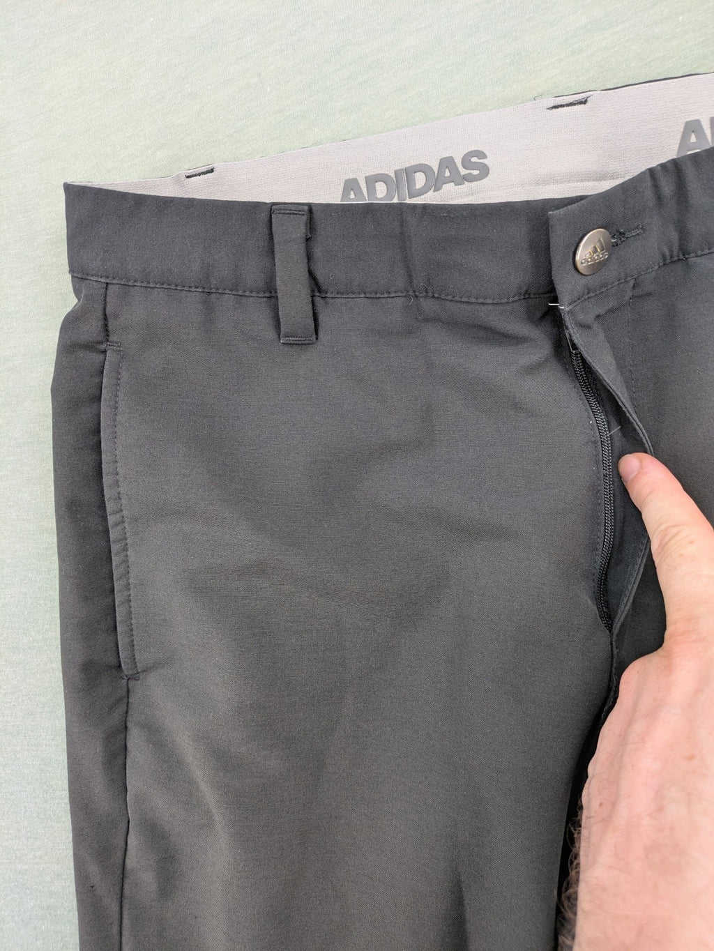 Adidas grey pants with 3-stripe logo, flat-front design, made from performance material.