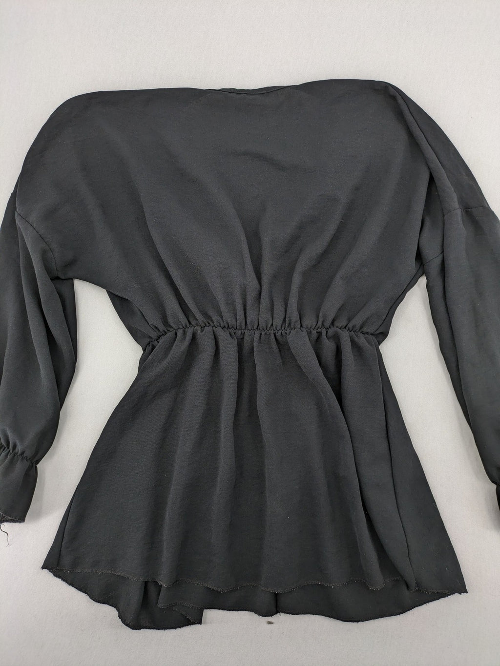 Bella black wrap blouse with deep V-neck and ruffled long sleeves.