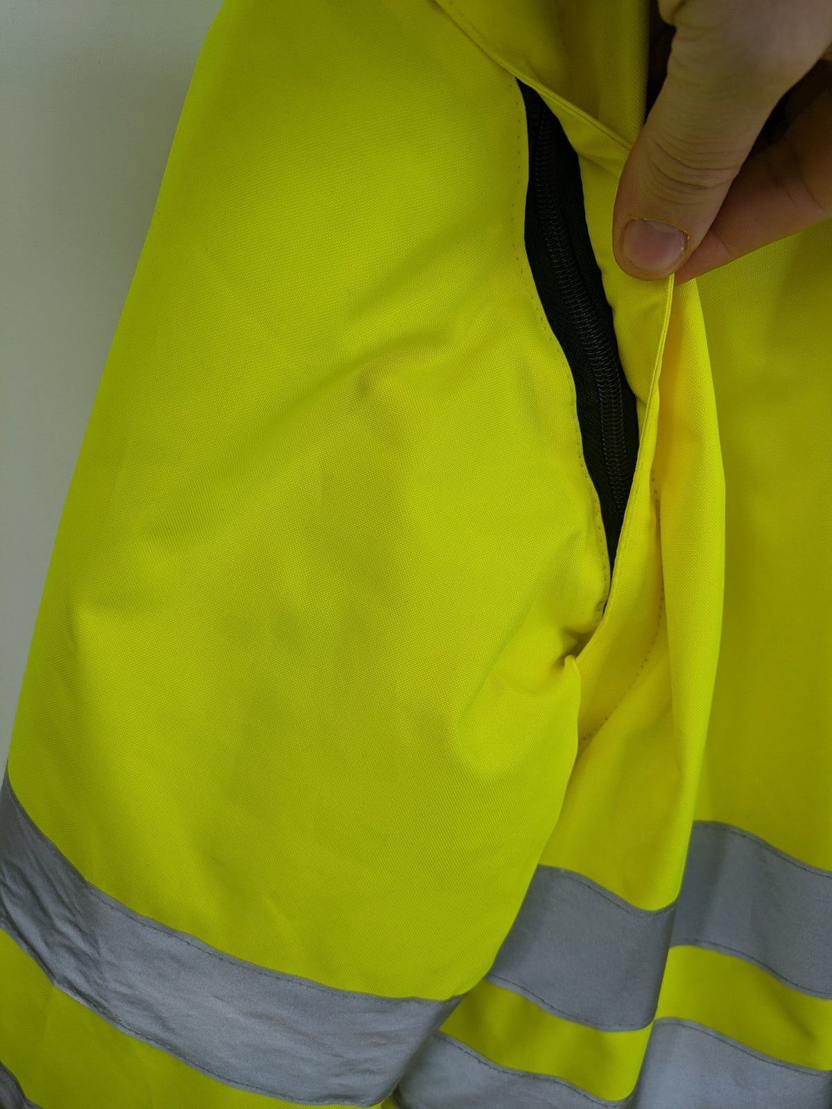 Hüren OHG grey and neon yellow safety jacket with reflective stripes and zippered arm pocket.
