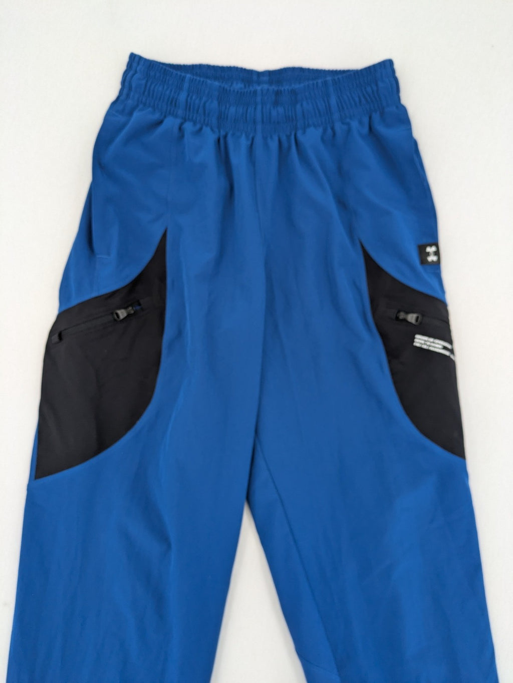 Under Armour blue HeatGear joggers with black accents and zippered cargo pockets.
