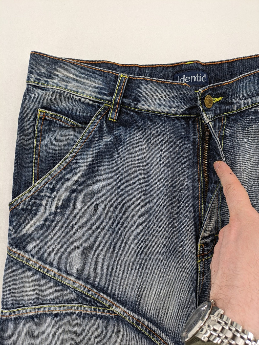 Identic orange straight jeans with paneled design and contrasting yellow stitching.