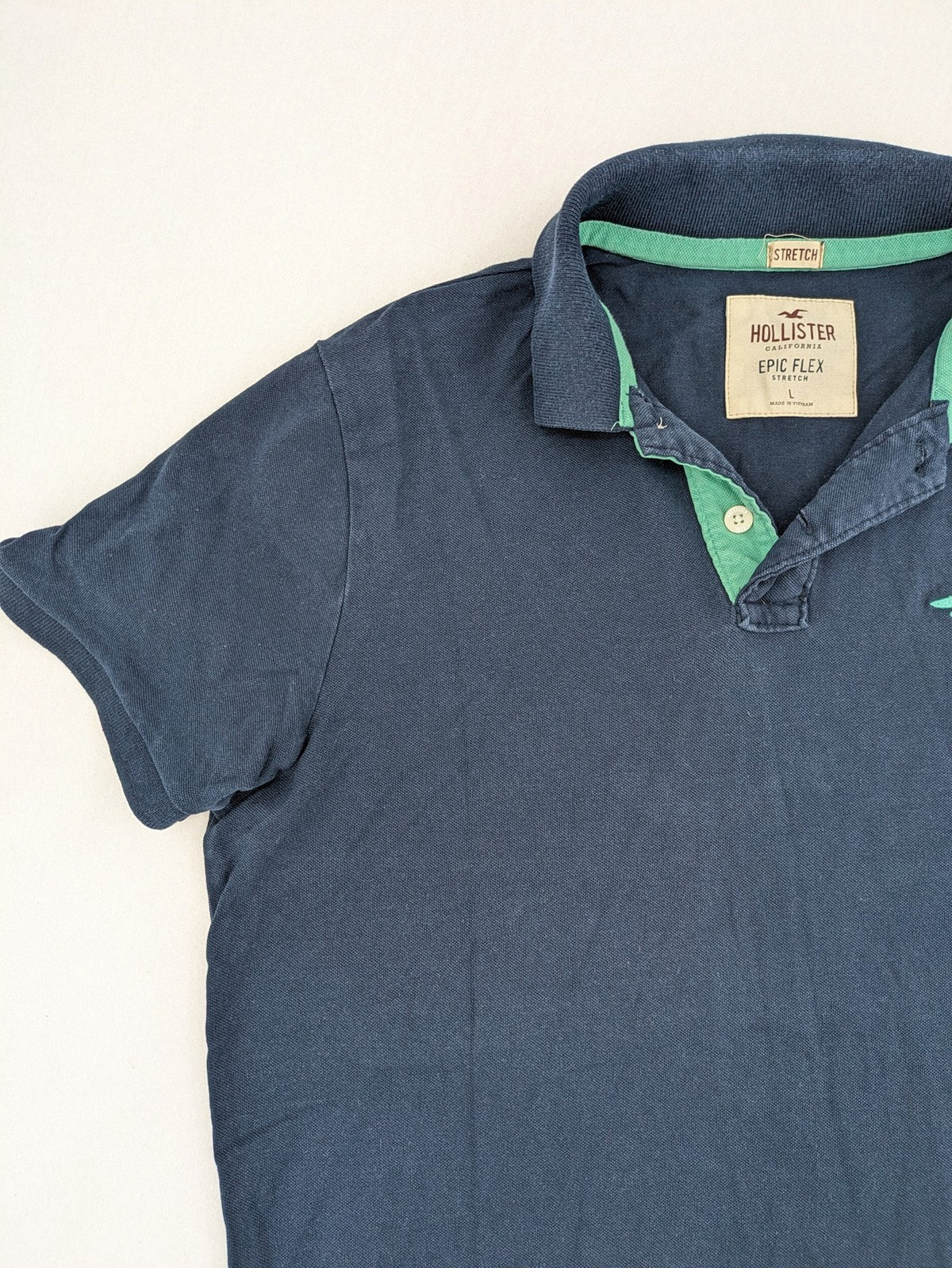 Hollister polo shirt navy blue with embroidered seagull logo and green trim.