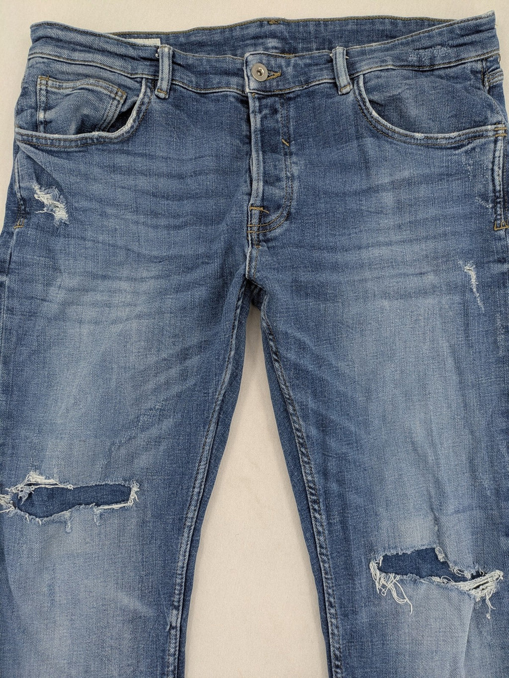 Zara blue straight jeans with distressed ripped knees and button-fly closure.