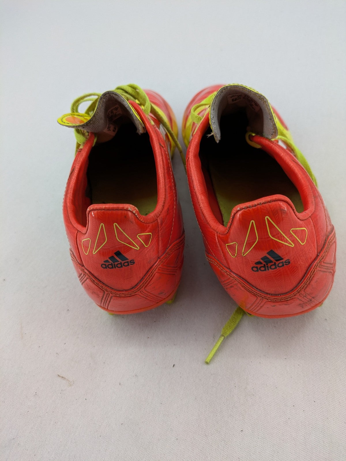 Adidas F50 soccer shoes red and yellow with three-stripe logo and lightweight synthetic material.