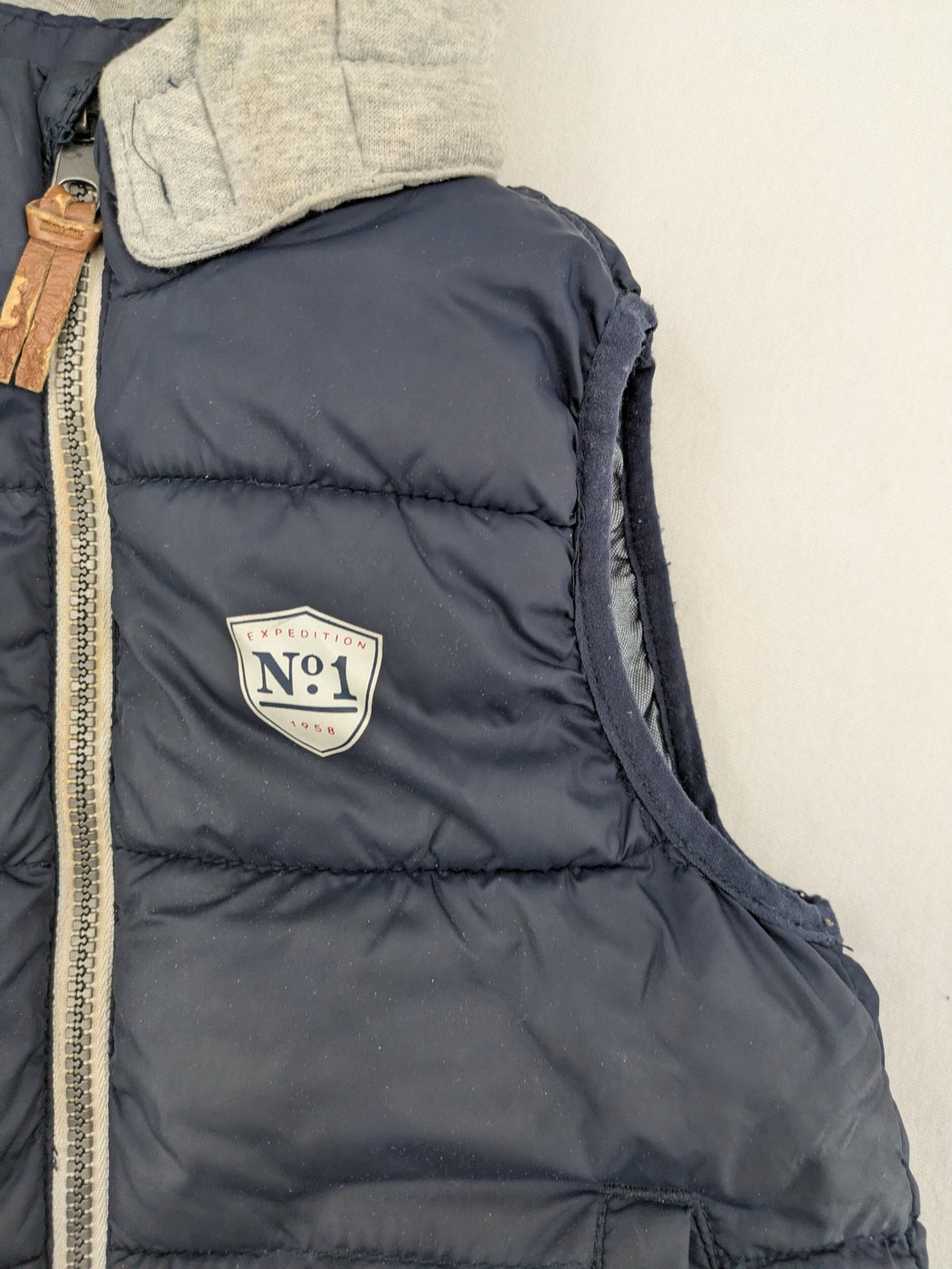 H&M navy puffer vest with grey hood and zip pockets for kids.