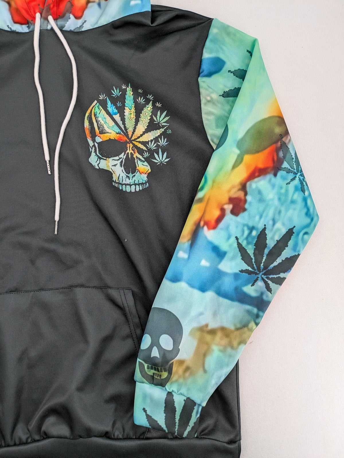 Skull tie-dye hoodie blue green with cannabis leaf graphic and bold text.