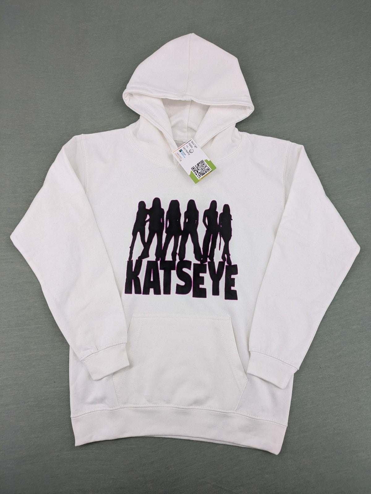 KATSEYE white zip-through hoodie with black silhouette graphic and logo, classic pullover style.