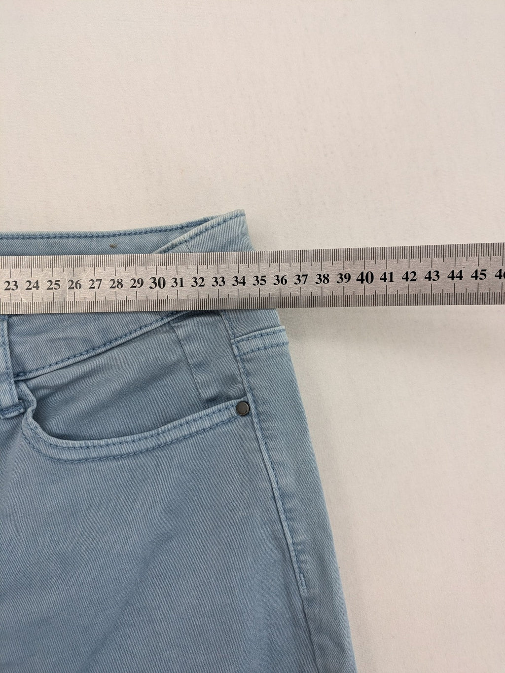 Yessica blue skinny jeans high rise with button fly and V-cut hem detail.