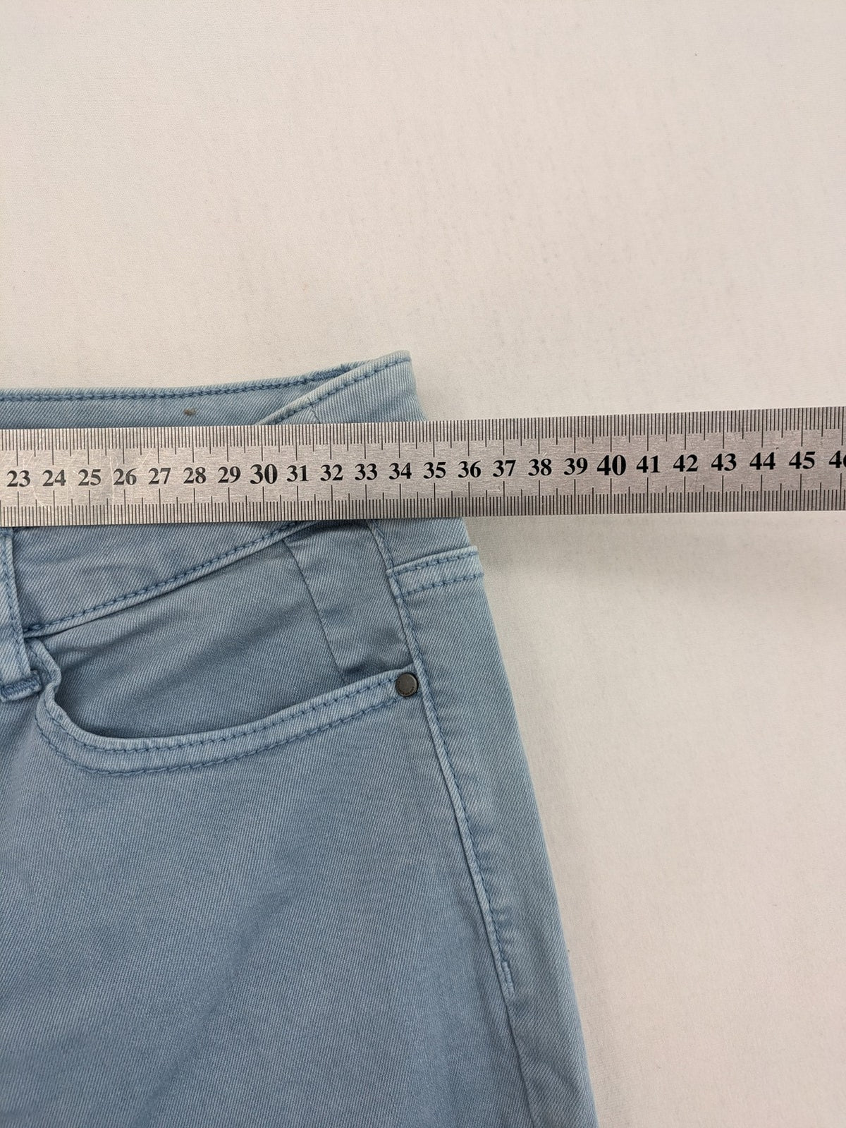 Yessica blue skinny jeans high rise with button fly and V-cut hem detail.