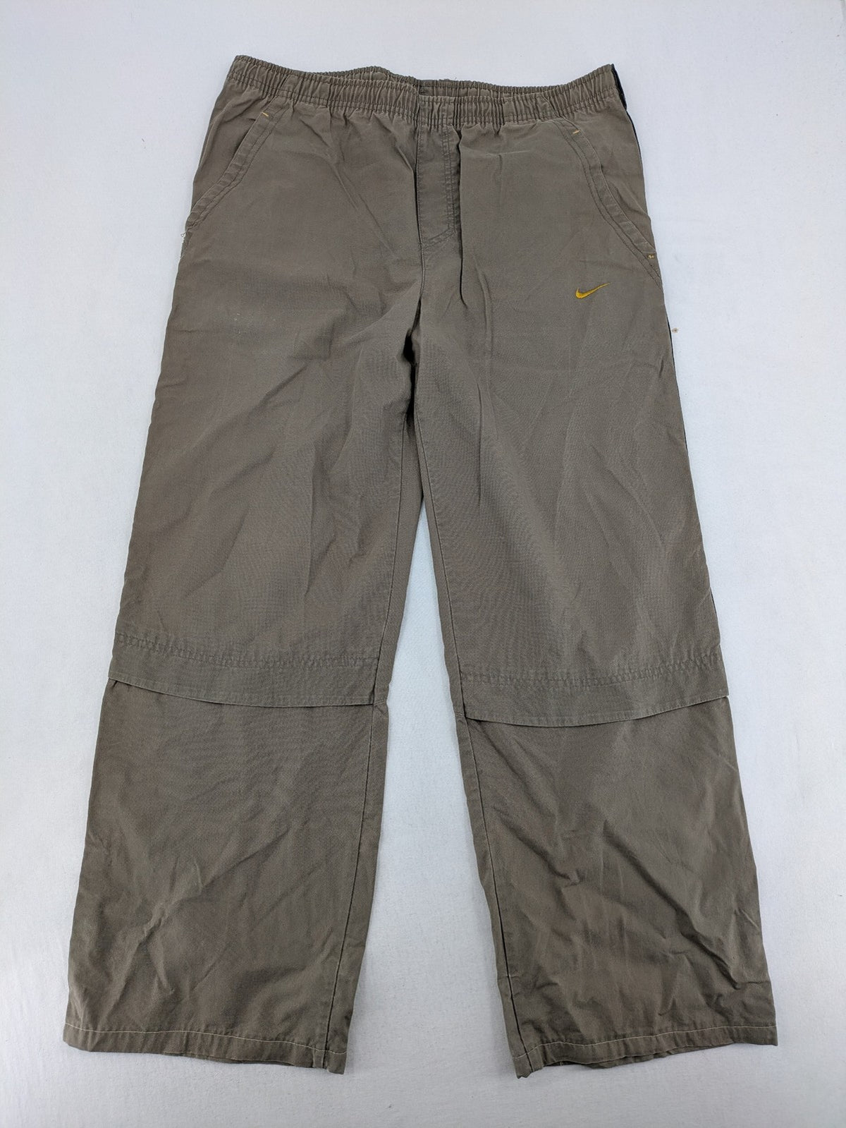 Nike khaki training pants with logo, elastic waistband, and practical pockets.