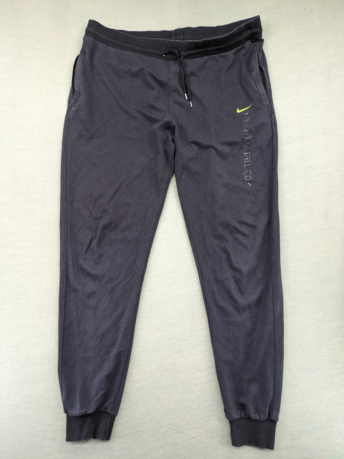 Nike F.C. grey jogger pants with elastic waistband, side pockets, and embroidered Swoosh logo.