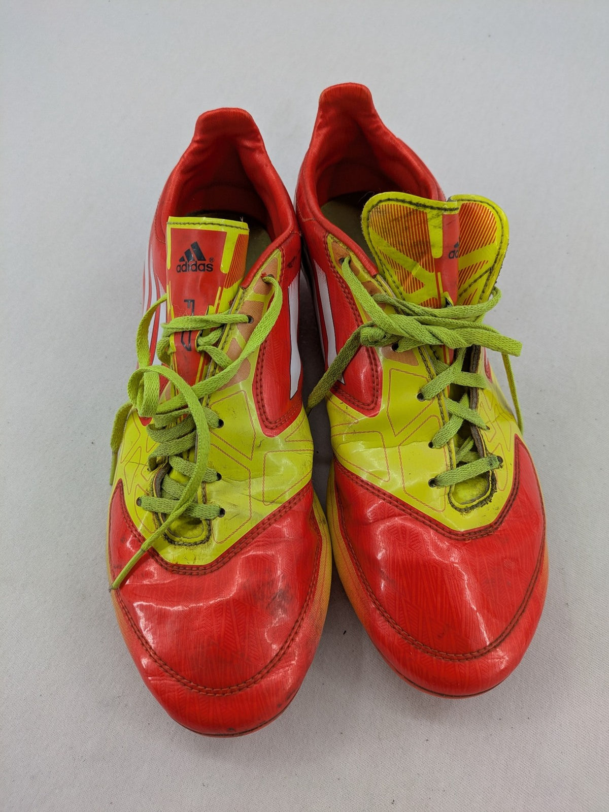 Adidas F50 soccer shoes red and yellow with three-stripe logo and lightweight synthetic material.