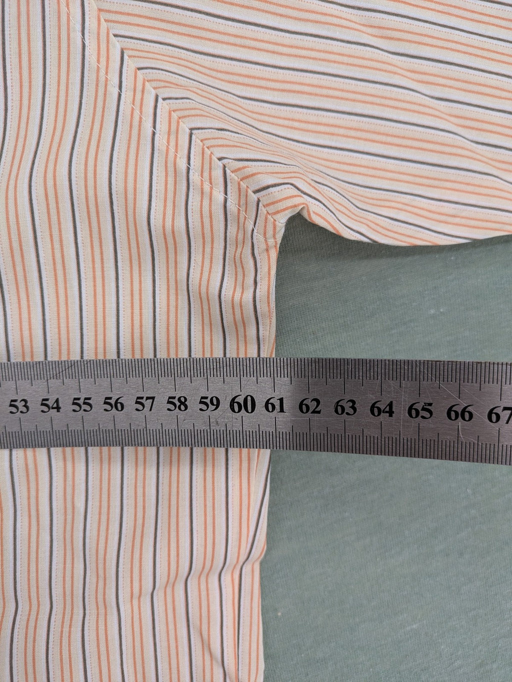 Ken Baker orange short-sleeve shirt with vertical stripes and chest pocket.