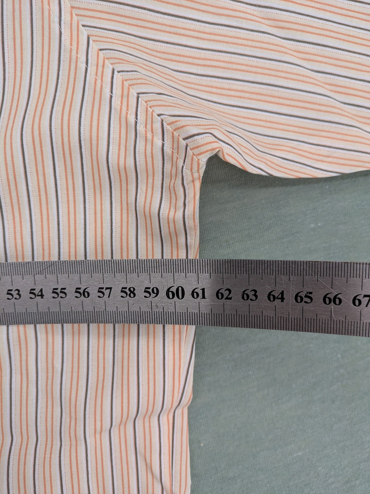 Ken Baker orange short-sleeve shirt with vertical stripes and chest pocket.