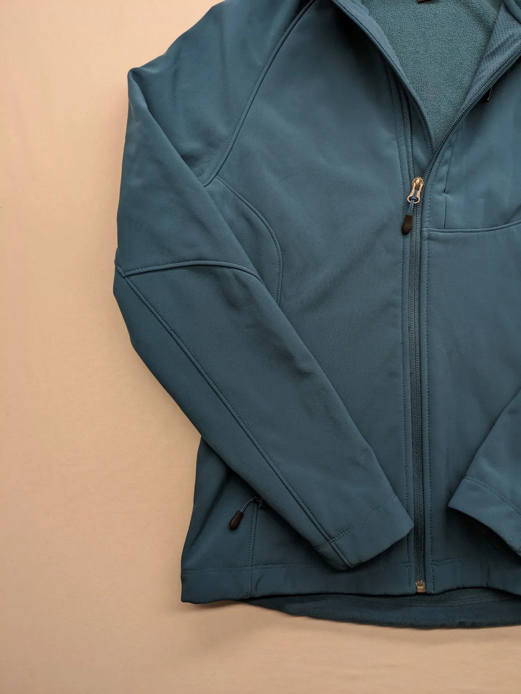 Kirkland Signature blue softshell jacket with hood, fleece lining, and zippered pockets.