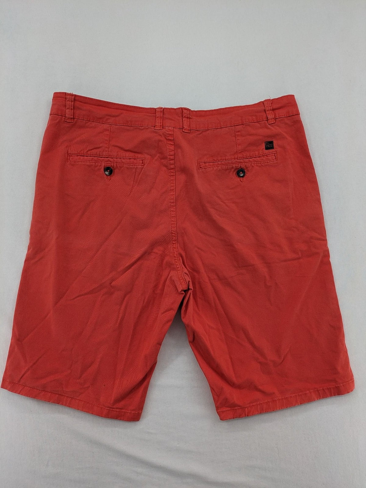 Chino orange shorts flat front with Est. 1921 label and comfortable fit.