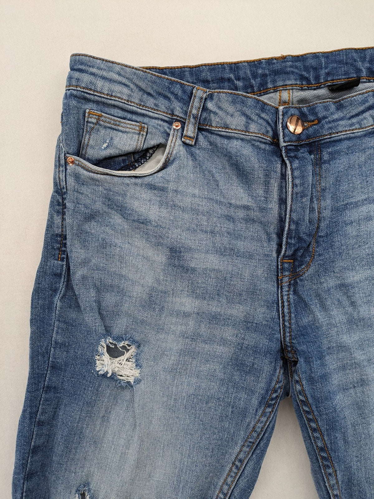 Denim blue distressed jeans shorts with frayed edges and a trendy used look.