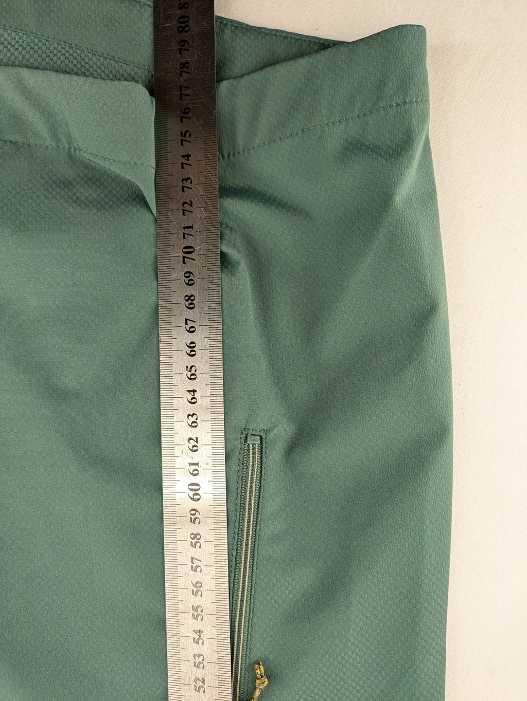 Frilufts green softshell jacket with hood, longline design, durable zipper, practical zip pockets.