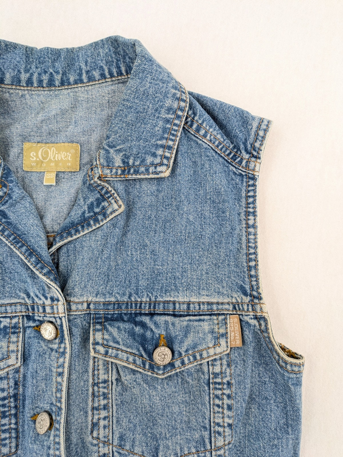 s.Oliver blue denim vest with button closure, pointed collar, and breast pockets.