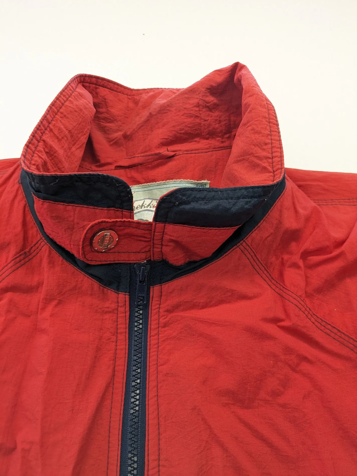 Bush Sportswear red trekking jacket with front zipper, multiple pockets, and striped lining.