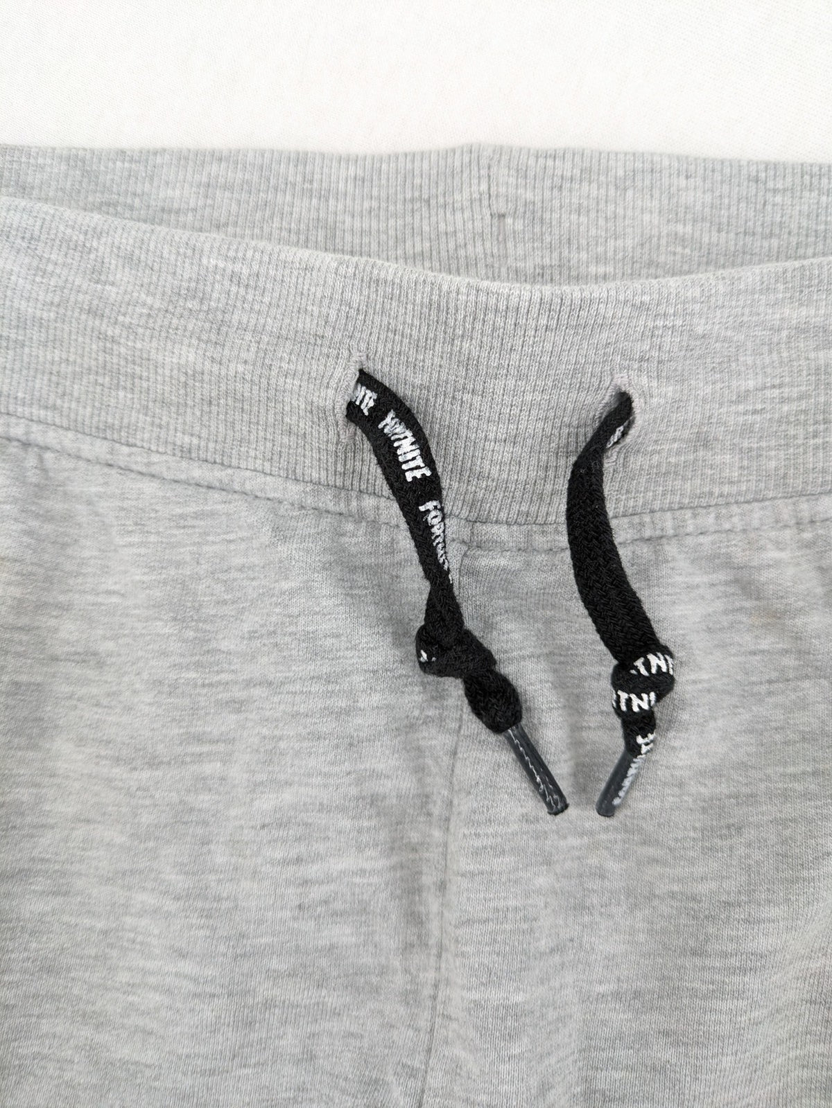 Fortnite pants grey with black side stripes and large logo print, cotton blend material.