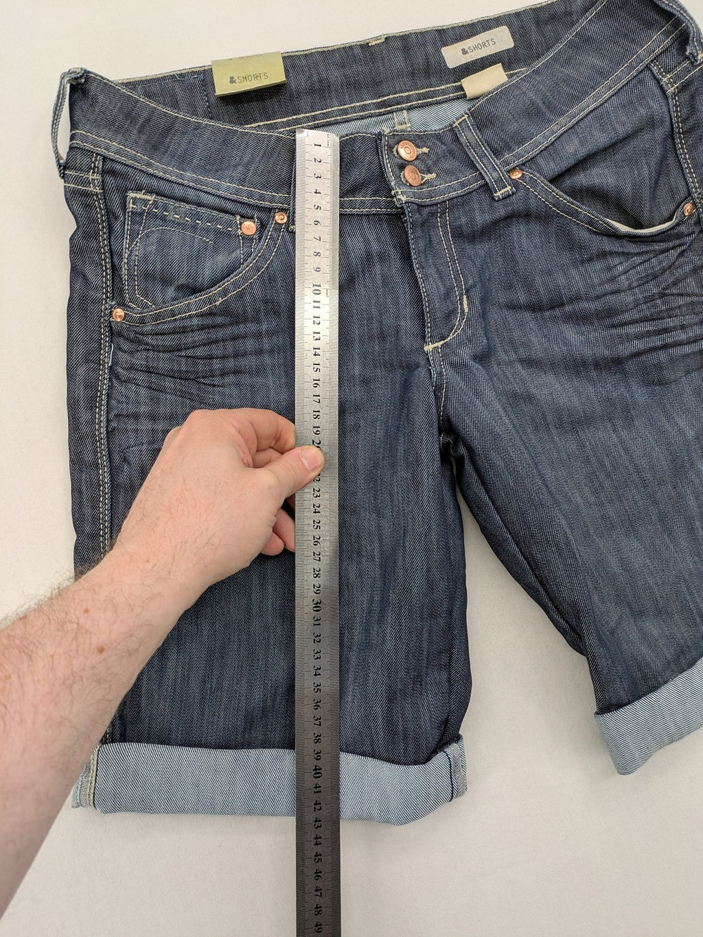 H&M blue denim shorts with rolled cuffs and back patch pockets, mid-rise fit.