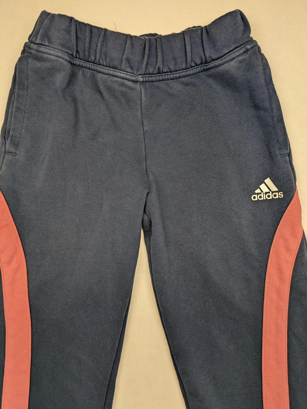 Adidas grey joggers with pink stripes and iconic logo on thigh.