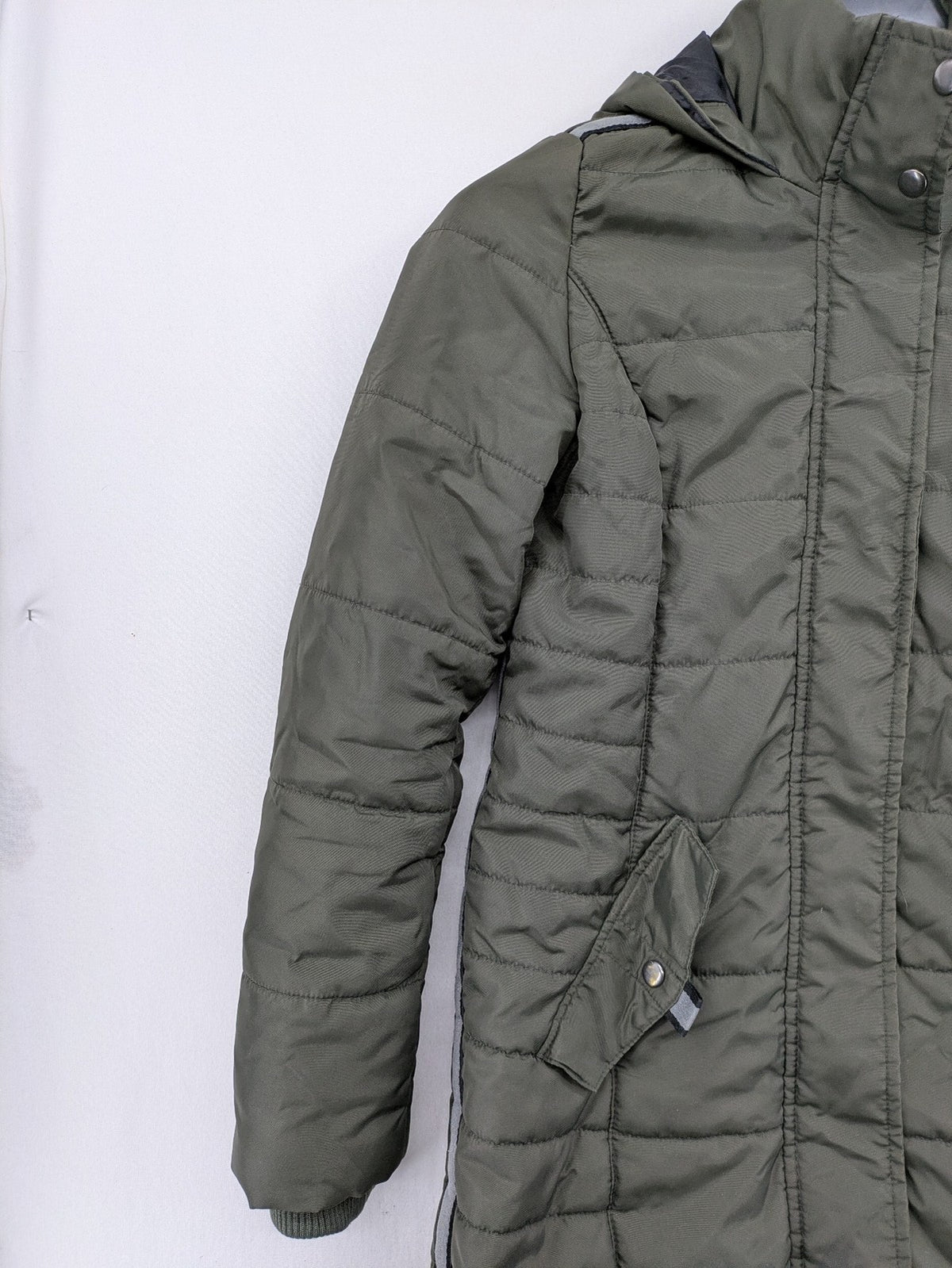Vero Moda green puffer coat with quilted design and hood, featuring zipper and button closure.