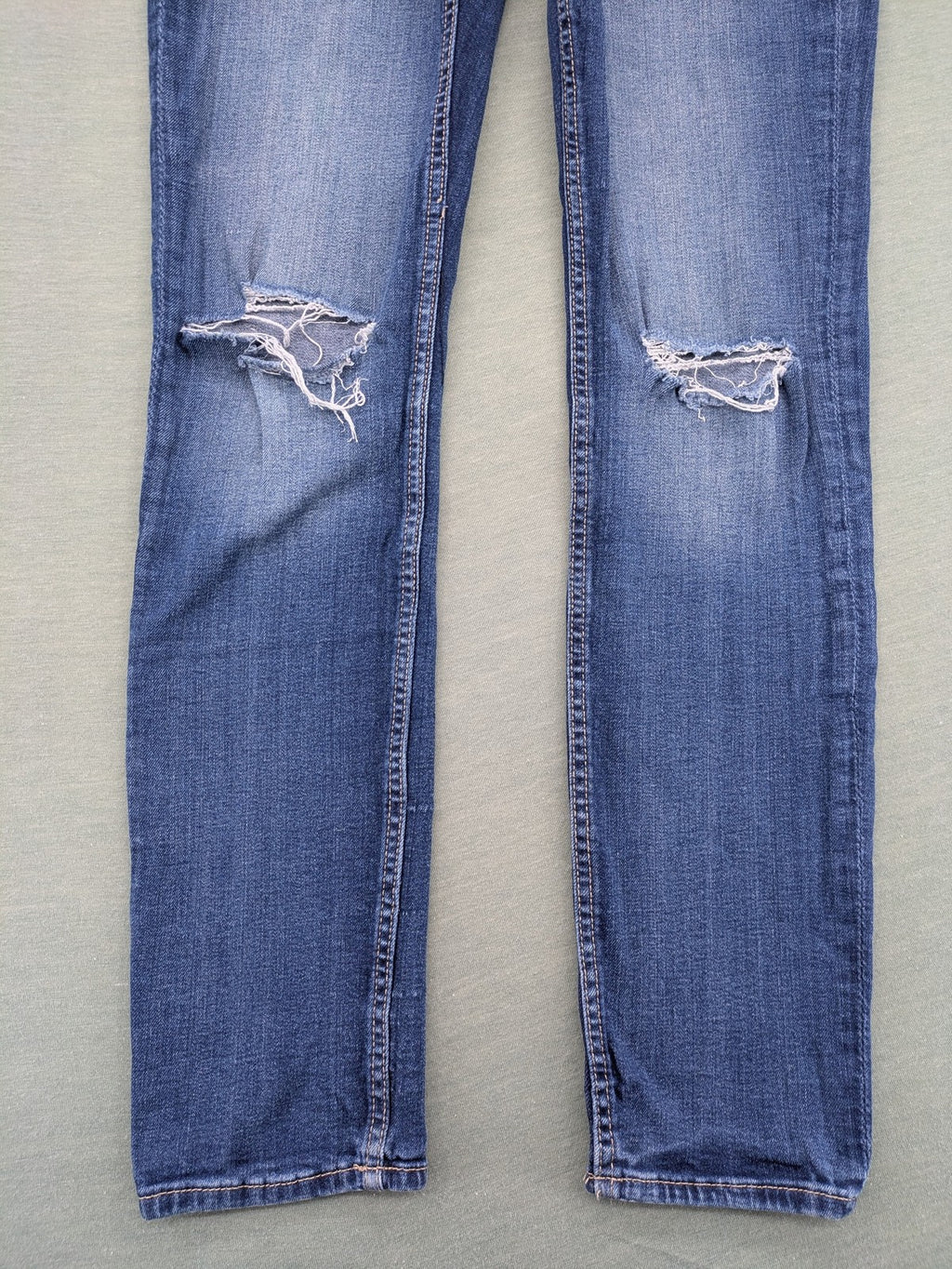 H&M blue skinny jeans with distressed knee details and classic 5-pocket design.
