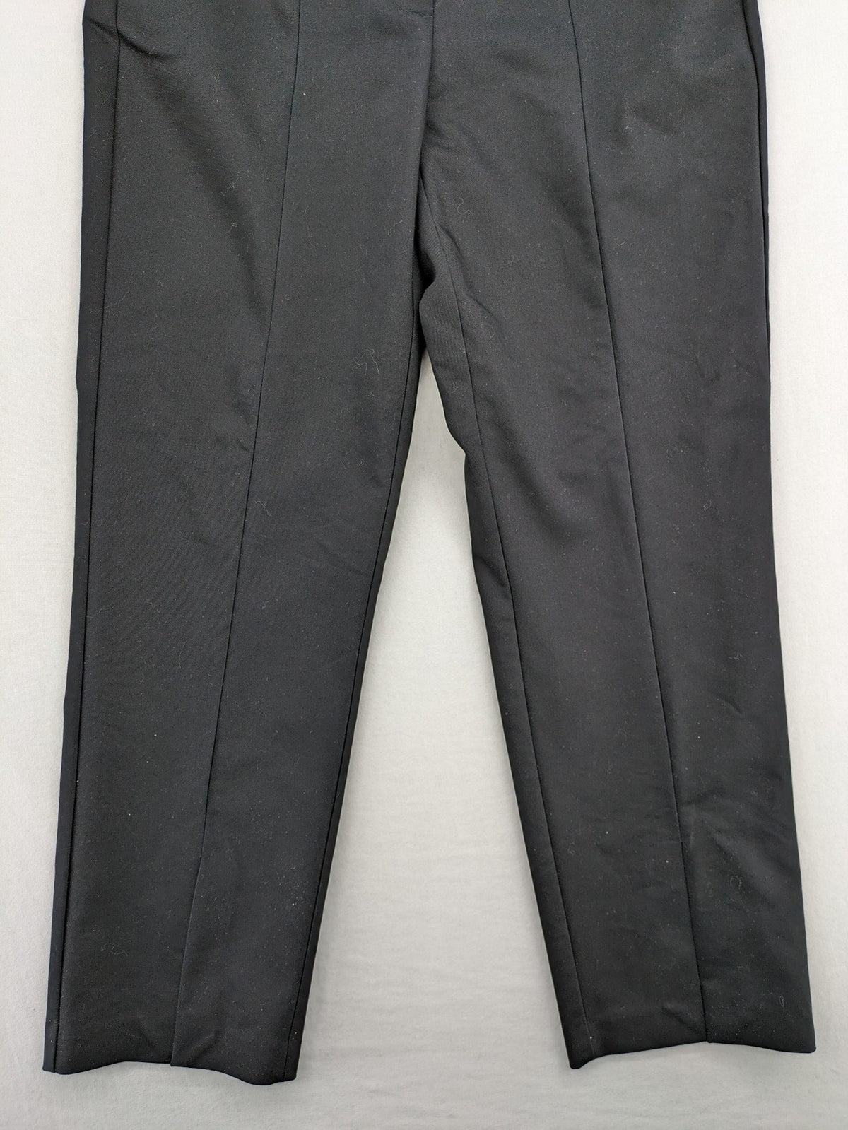 Zara black pants with front creases, subtle slit hem, and buttoned back pocket.