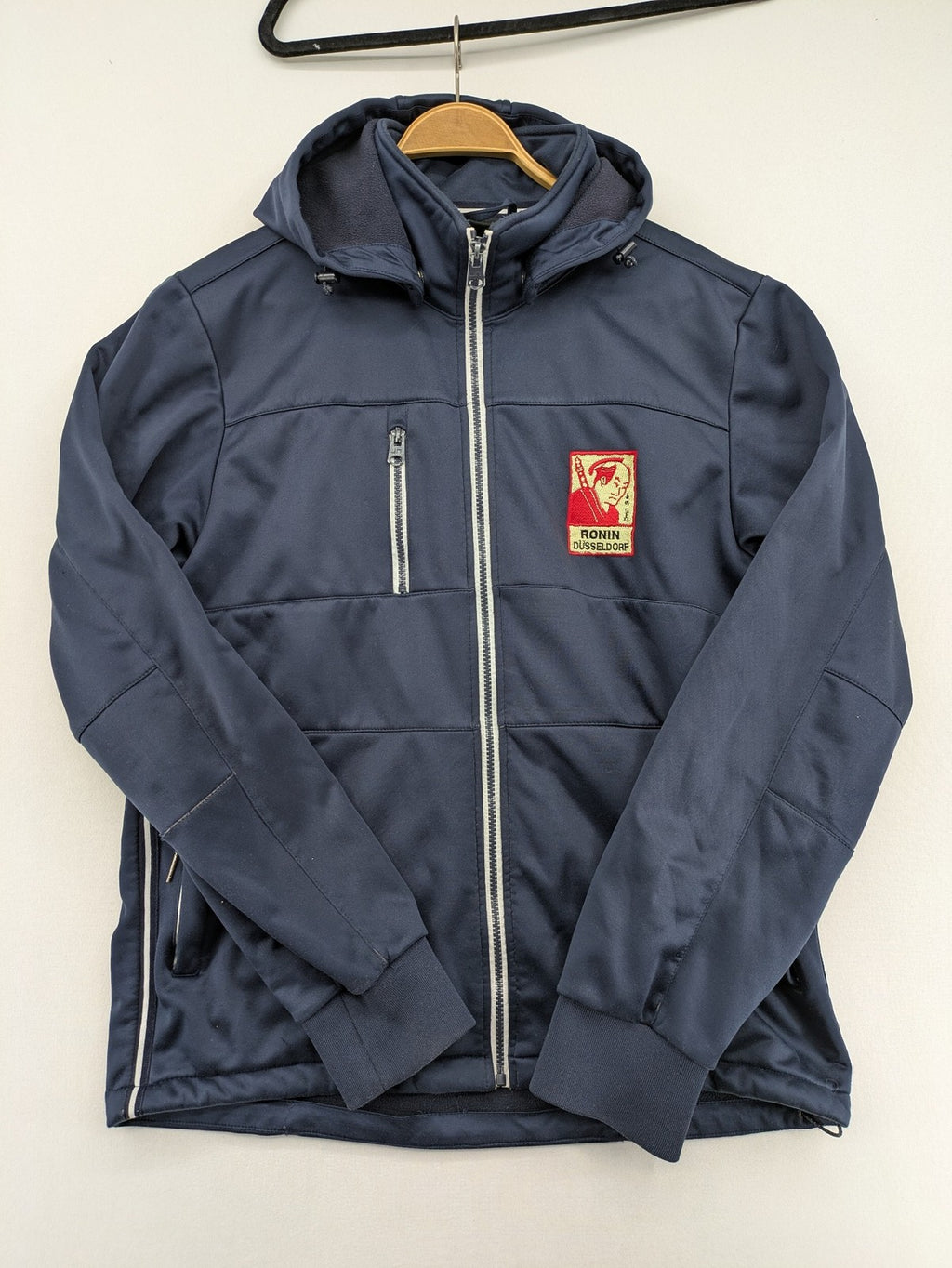 James & Nicholson beige softshell jacket with fleece lining and embroidered Ronin Düsseldorf patch.