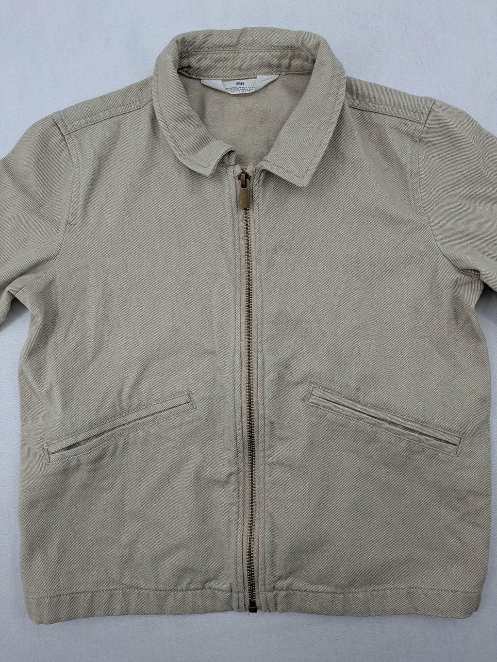 H&M beige twill coat with full zip, classic collar, and practical pockets.