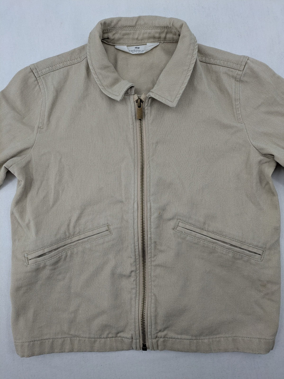 H&M beige twill coat with full zip, classic collar, and practical pockets.