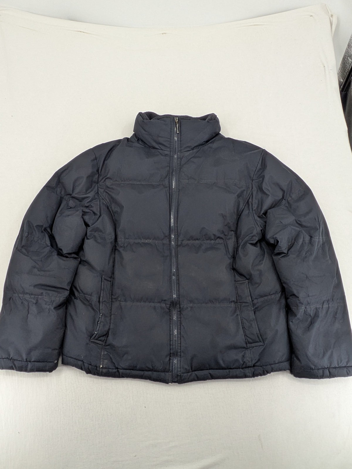 Identic black puffer jacket with quilted design and fleece-lined high collar.