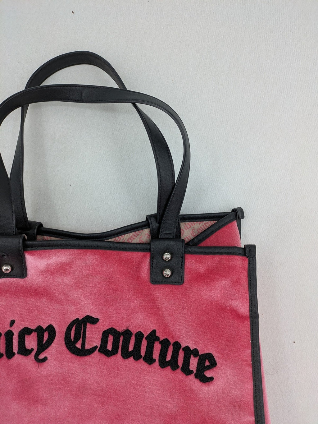 Juicy Couture pink velour handbag with oversized black logo and faux leather straps.