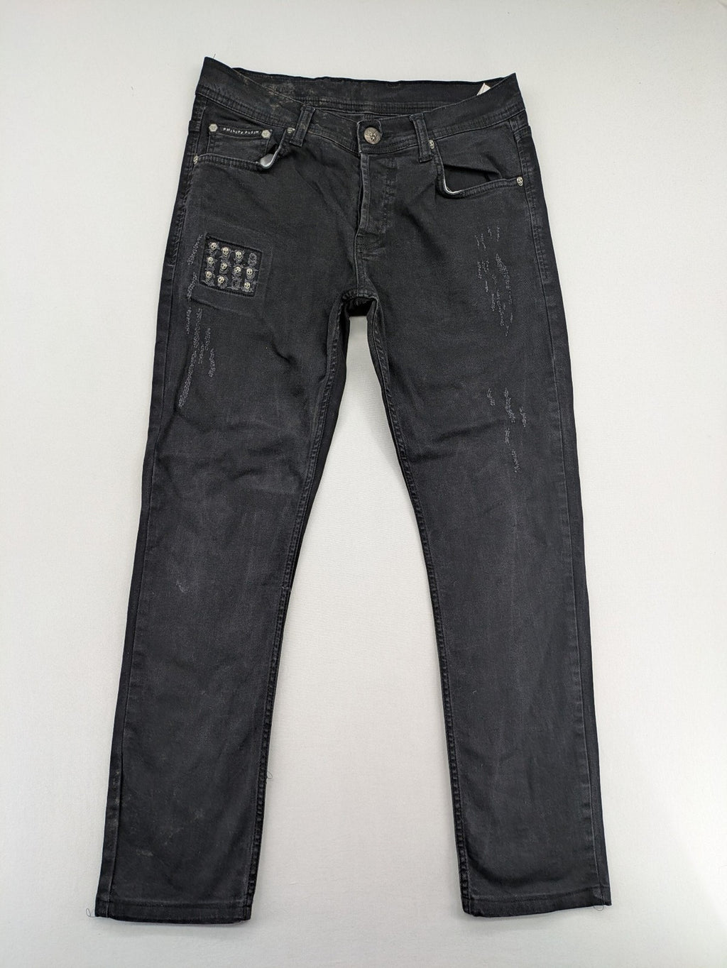 Philipp Plein black straight jeans with distressed finish and skull patch detail.