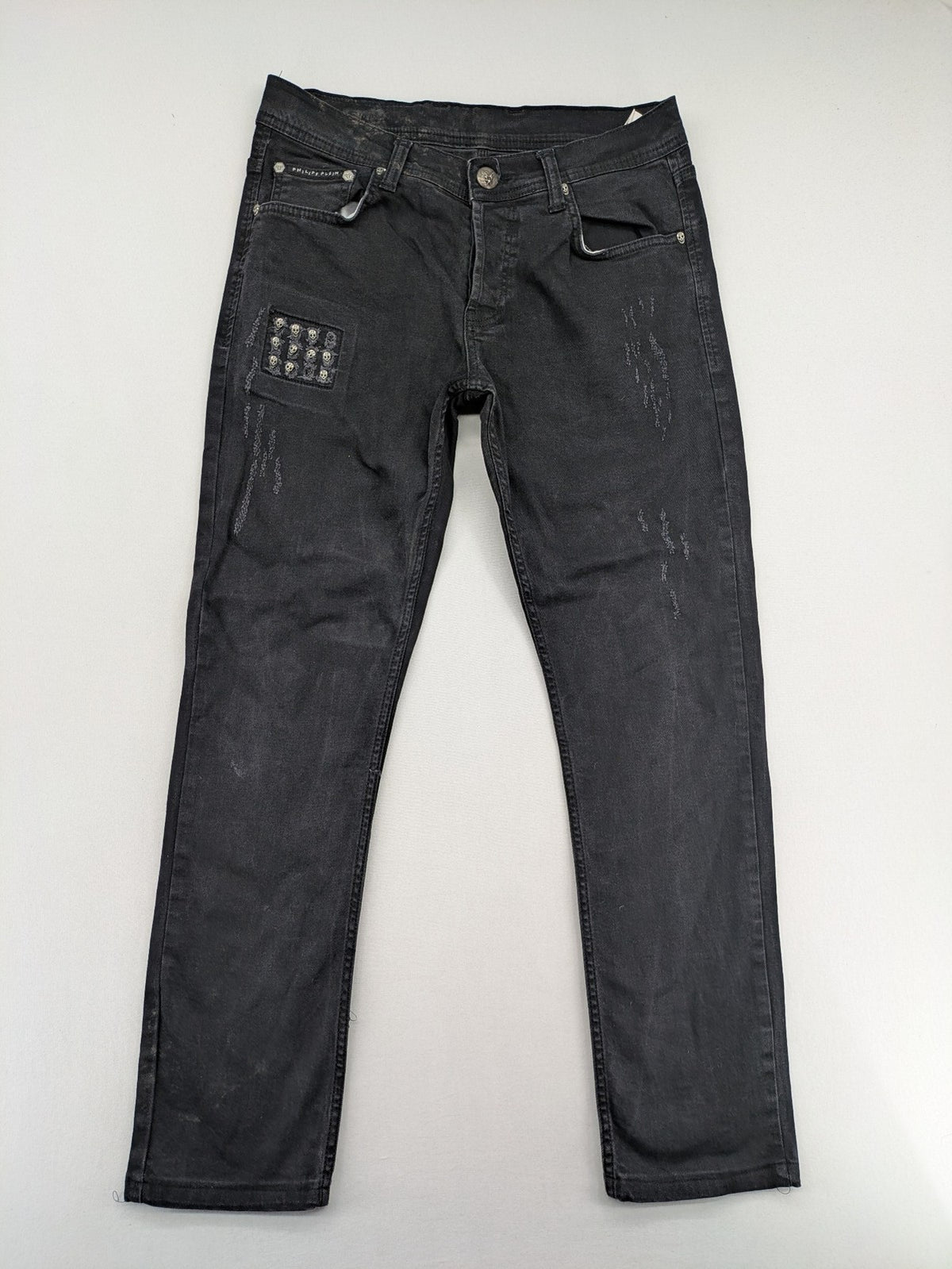 Philipp Plein black straight jeans with distressed finish and skull patch detail.