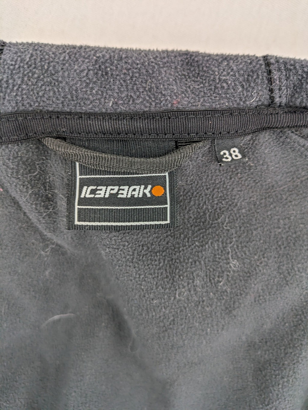 Icepeak black softshell jacket with fleece lining, adjustable hood, and zippered pockets.