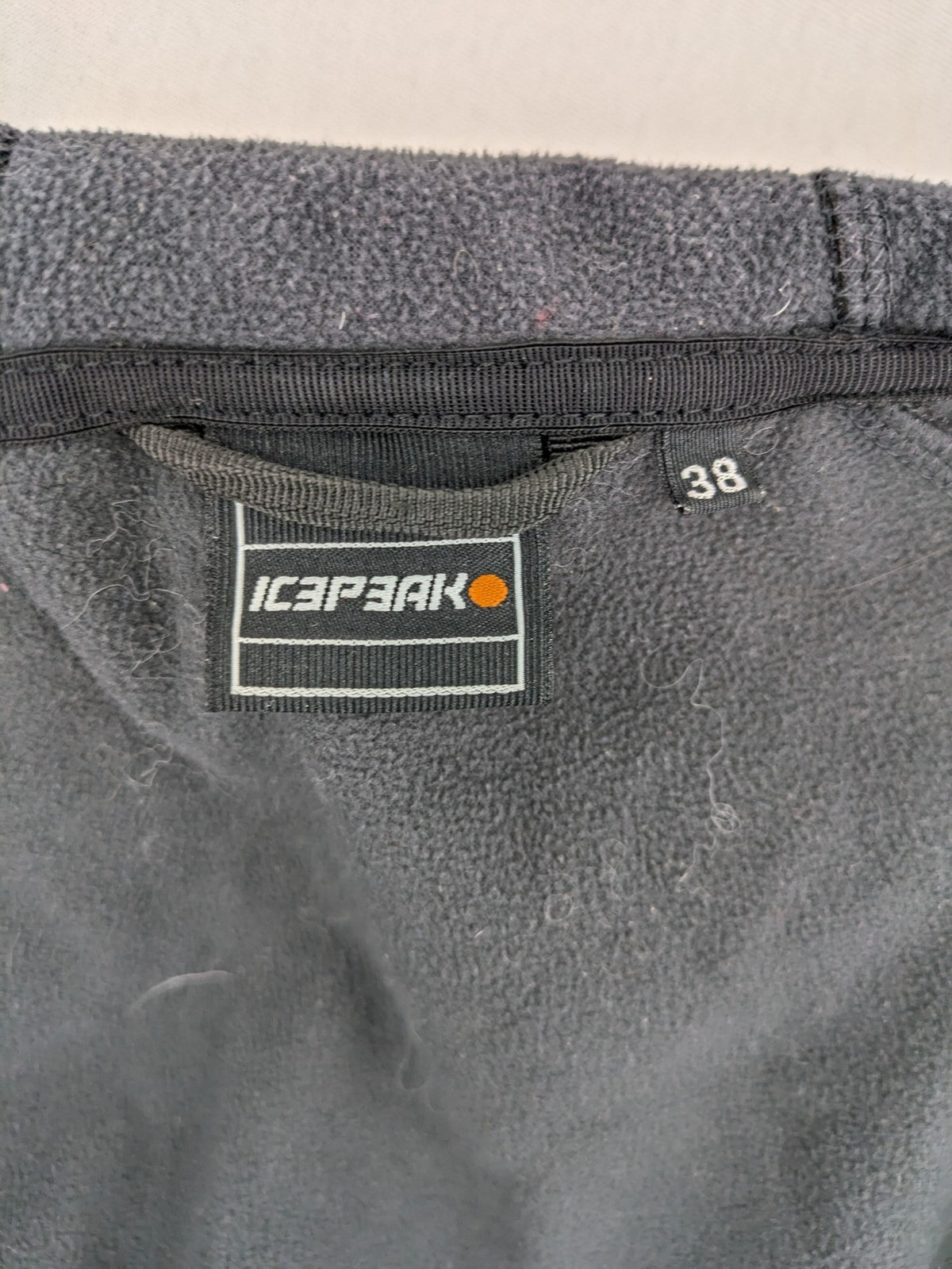 Icepeak black softshell jacket with fleece lining, adjustable hood, and zippered pockets.