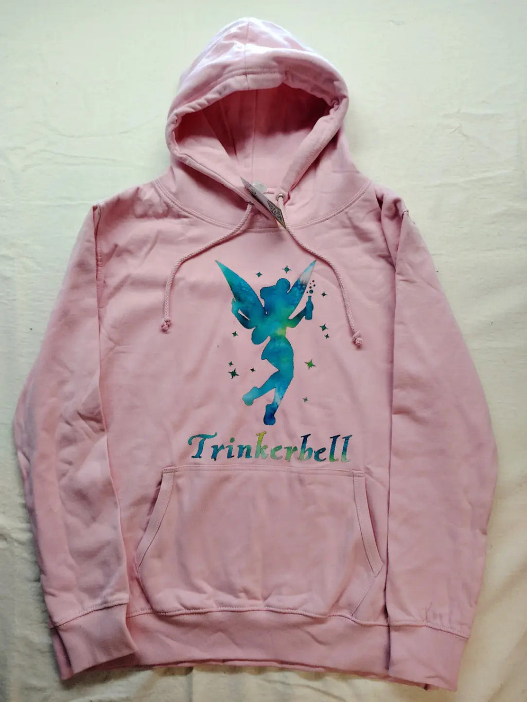Just Hoods pink zip-through hoodie with "Trinkerbell" graphic, kangaroo pocket, drawstring hood.