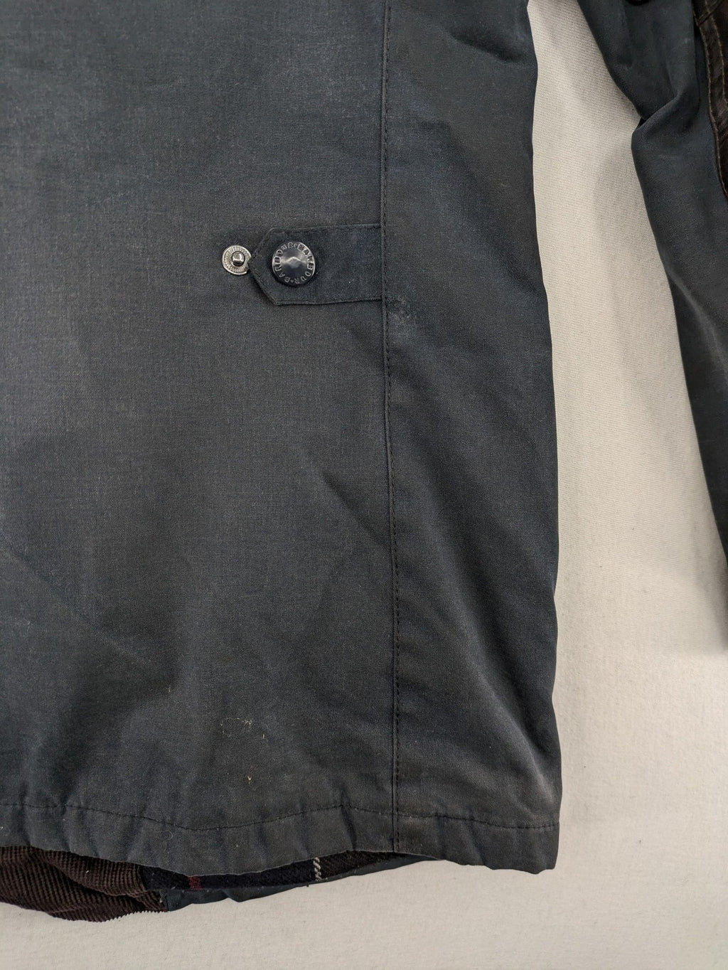Barbour navy wax jacket with quilted lining and leather elbow patches, tartan interior.