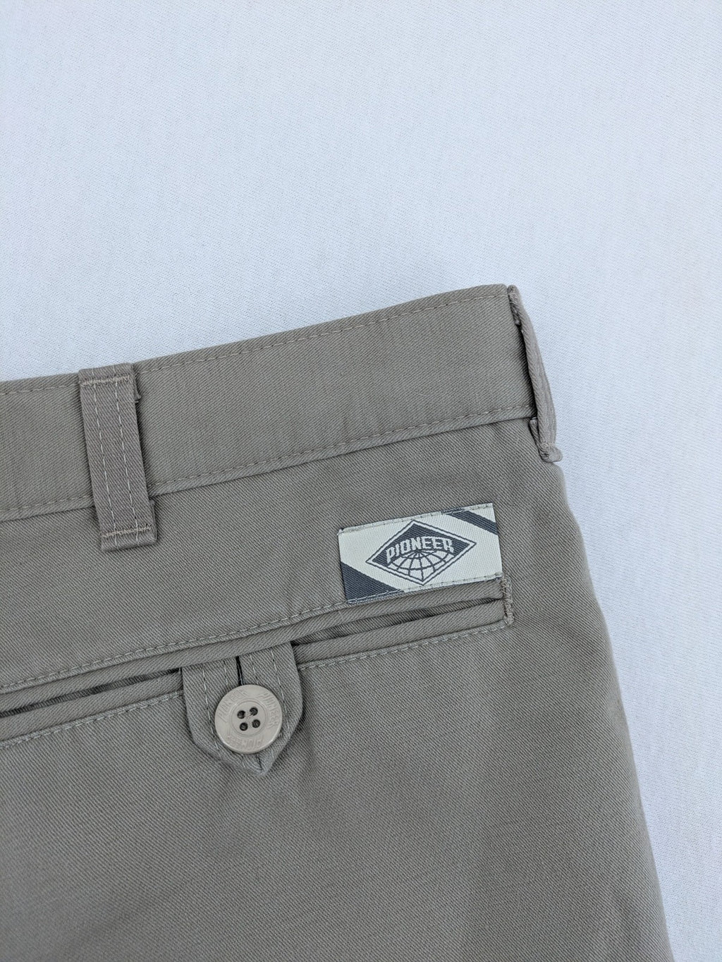 Pioneer beige chino trousers with pleats, straight leg, and buttoned back pocket.