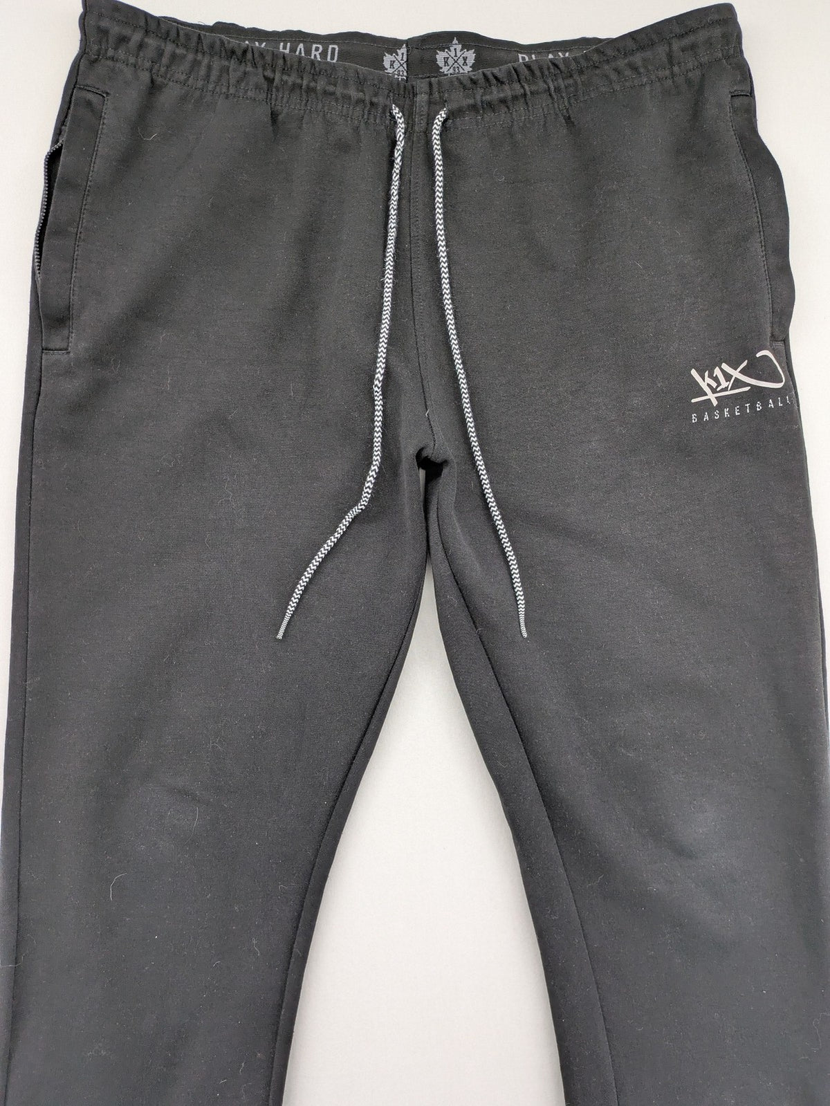 K1X grey joggers with white basketball logo, elastic waistband, and cuffed ankles.