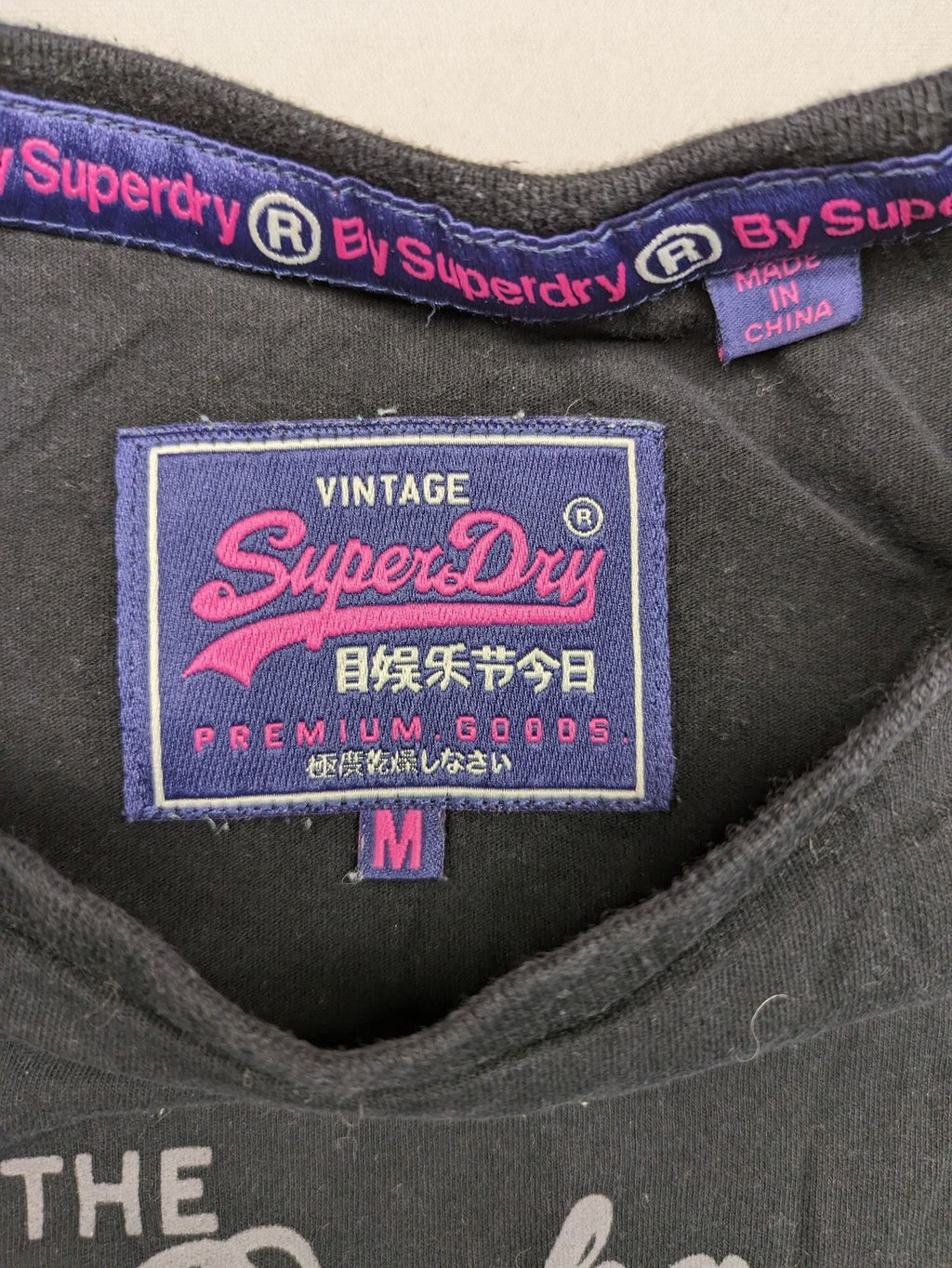 Superdry black t-shirt with large Osaka Brand logo and subtle floral pattern.